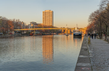 Fototapeta premium Paris, France - 12 28 2019: Reflections of buildings at the basin of the villette at sunset