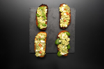 Several avocado sandwiches. Sandwiches with avocado on a black background.View from above. Flat lay.