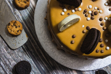 Drip chocolate cake with cookies on wood surface