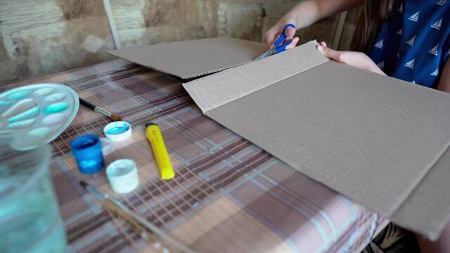 a girl cuts off cardboard to draw a picture - creative activity at home