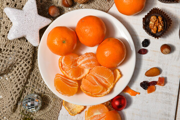sweet food background for christmas or holiday decoration - chocolate candies, tangerines, nuts and dried fruits on white wood