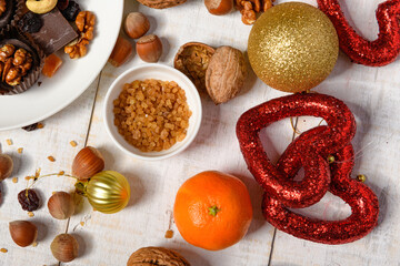 sweet food background for christmas or holiday decoration - chocolate candies, tangerines, nuts and dried fruits on white wood