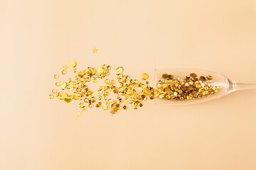 Glasses with golden confetti tinsel on beige background. Flat lay, top view, copy space. Celebrate party concept