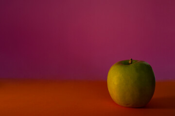 Green apple on a table with vibrant color background - Copy space