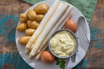 Ingredients for spring vegetarian dinner, high quality Dutch white asparagus, washed and peeled on board, ready to cookand, young potatoes, eggs and sauce