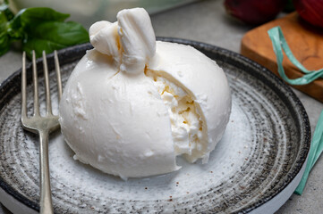 Eating of fresh handmade soft Italian cheese from Puglia, white balls of burrata or burratina cheese made from mozzarella and cream filling