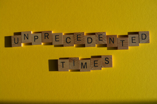 Unprecented Times, phrase in wooden alphabet letters isolated on yellow background