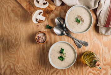 Mushroom cream soup in gray bowls with parsley on wooden background
