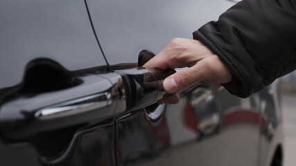 man in black jacket opens door of black minivan with his hand, press button and door slides to the side.