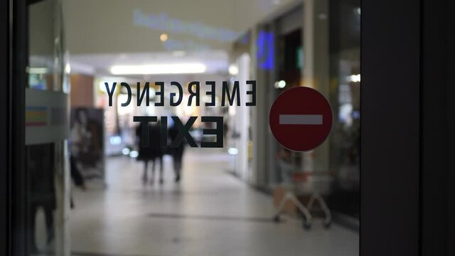 Emergency exit sign on empty city mall during pandemic