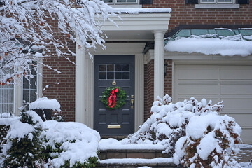 Front door with evergreen wreath with snow covered steps