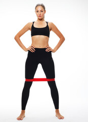 Athletic woman goes in for sports with a rubber band on legs. Inflated leg muscles in leggings. Over white background.