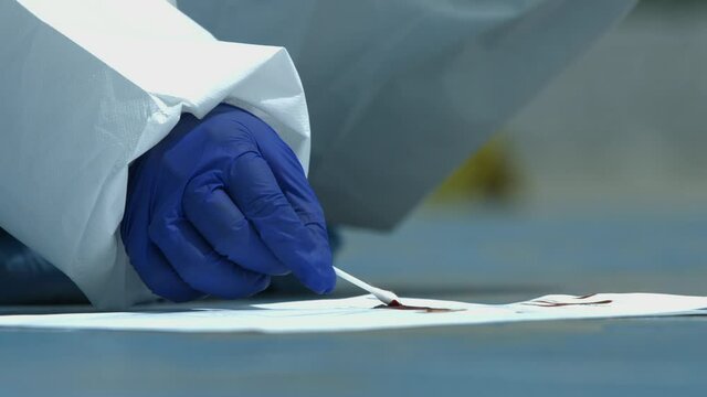 human hand collecting blood samples at the crime scene with a cotton swab and inserting a pipette