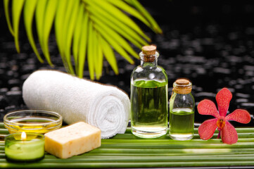 Obraz na płótnie Canvas Beautiful spa setting of frangipani withrolled towel ,soap, green palm on pile of long bamboo stem background