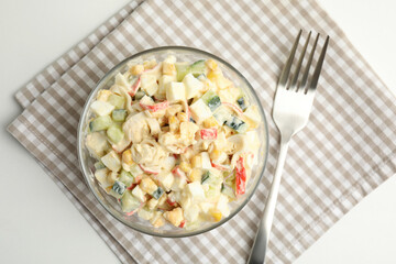 Delicious salad with fresh crab sticks in glass bowl on white table, top view