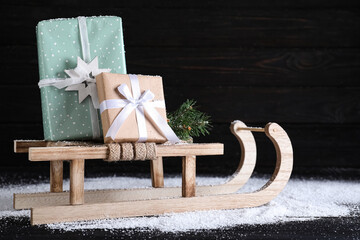 Sleigh with gift boxes on black wooden table