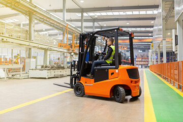 Storehouse employee in uniform working on forklift in modern automatic warehouse. Boxes are on the shelves of the warehouse. Warehousing, machinery concept. Logistics in stock. - obrazy, fototapety, plakaty