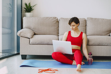 Girl at home. Woman make yoga. Lady in a red sports uniform.