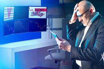Investor is looking at the tablet. An upset investor holds his head. Concept - a man reads financial market news. Man learned about the crisis in the economy. Quotes and charts on monitors.