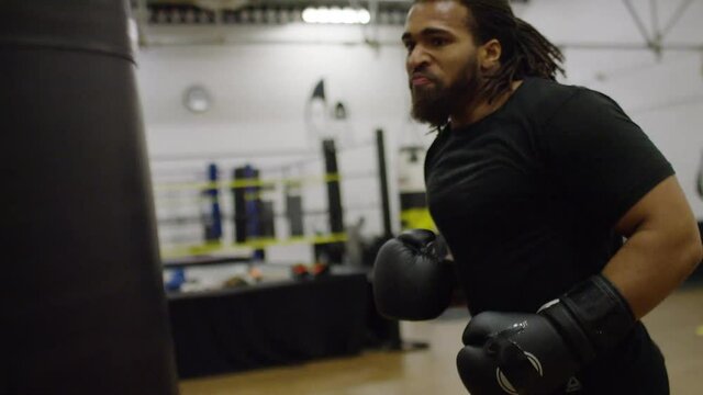 Male boxer in the gym working out on a punchbag, in slow motion