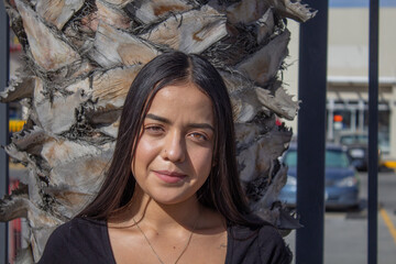 portrait of beautiful Mexican girl in front of palm tree. hispanic woman