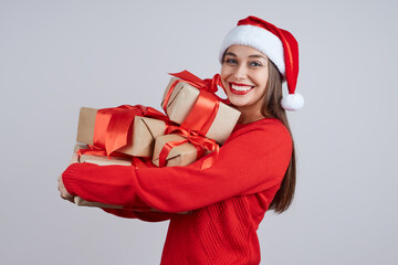 Laughing woman in santa hat, red sweater, holding a bunch of gifts with a red ribbon. Holiday concept, Christmas, New Year.