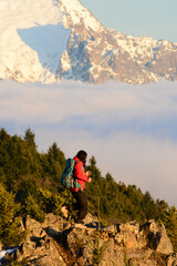 Single man hiking with backpack against gloomy mountainous landscape with cloudy sky, rocky mountain ranges and peaks and clouds. Extreme internal travel and trekking. 