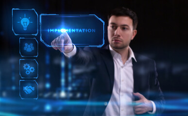 Business, Technology, Internet and network concept. Young businessman working on a virtual screen of the future and sees the inscription: Implementation