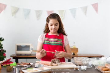 Happy child girl grinding biscuit crumbs on a mixer. Smiling girl baking Xmas cookies in the kitchen at home. Cooking traditional festive sweets and Christmas holiday celebration concept