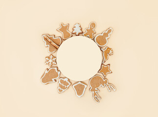 Christmas ornament with gingerbread cookies. Empty circle space for text and christmas cookies canvas around, flat lay or top view. Christmas baking on pastel beige, champagne background