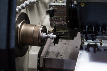 Fototapeta na wymiar CNC lathe or turning machine cutting thread at the end of metal part. Industrial metalwork machinery