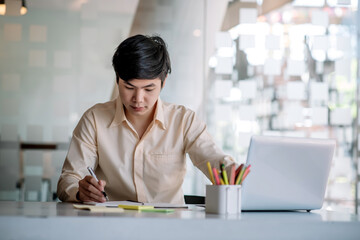 Young asian businessman sitting working with laptop computer in a modern office.