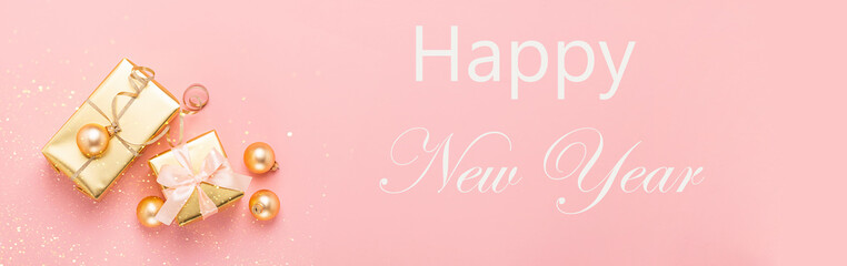 Festive boxes with satin ribbon bow golden toy balls a pastel pink background