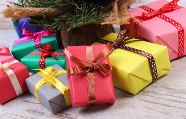 Wrapped colorful gifts for Christmas with christmas tree on old white plank