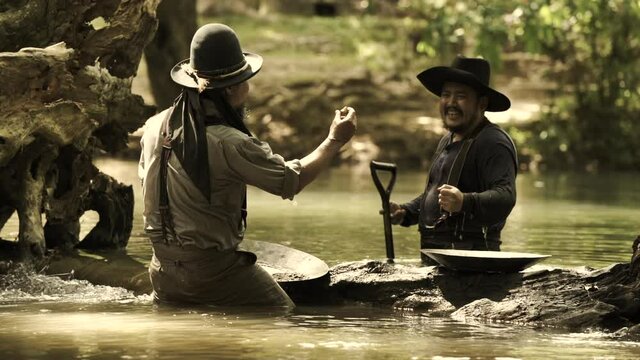 Cowboys, two men panning for gold by the river.