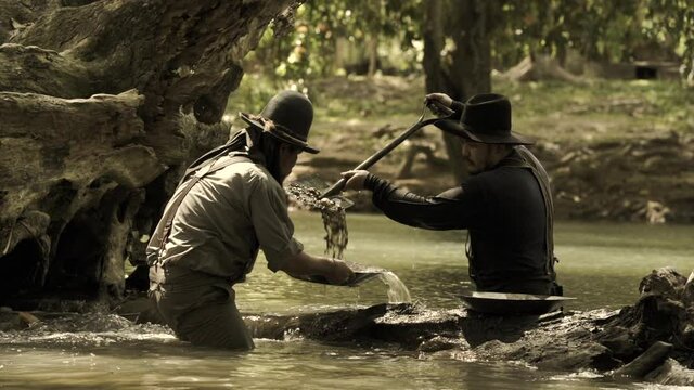 Cowboys, two men panning for gold by the river.