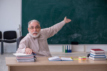 Old male teacher sitting in the classroom