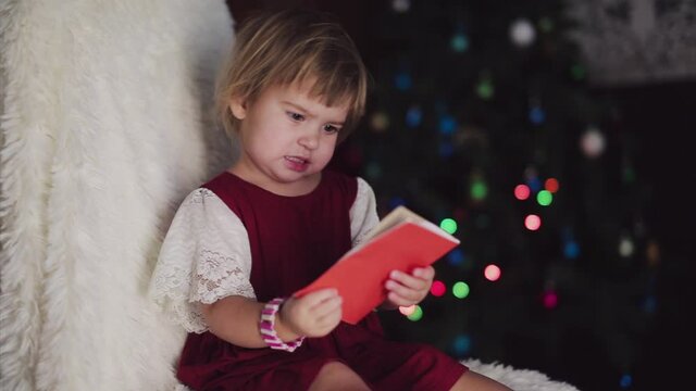 a child in red clothes is sitting waiting for the new year. the concept of celebrating Christmas at midnight. holiday costume. a girl writes a letter to Santa Claus. wish list