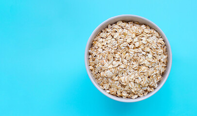 Oat flakes in bowl on blue background. Healthy food concept