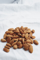 Almond kernels on white fabric. A handful of nuts on the tablecloth. Food for vegans, ingredients for making almond milk