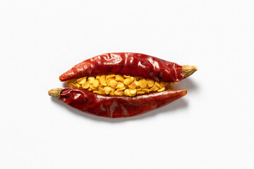 Two dried red peppers and some chili seeds on white background. Dried chili peppers creatively shaped.