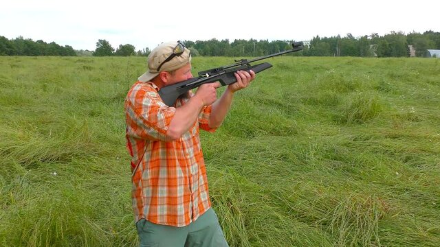 Hunter at cap and sunglasses aiming a gun