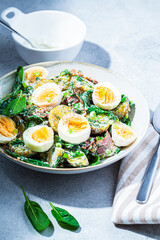 Traditional potato salad with bacon and eggs in white bowl. Picnic food concept.