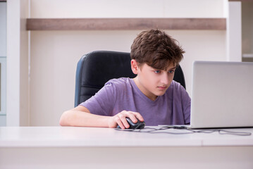 Schoolboy playing computer games at home