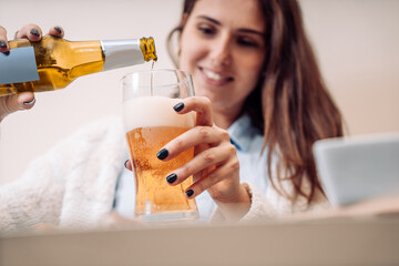 young woman pours a bottled beer into the glass