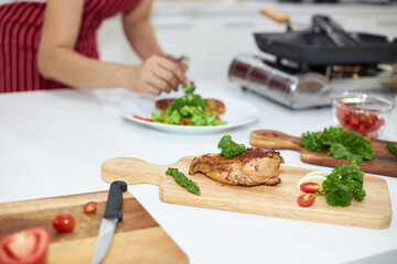 Asian woman making a steak in the kitchen.