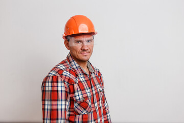 a man in a plaid shirt and an orange protective helmet on his head on white background.