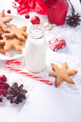 Fototapeta na wymiar Cookies, candy cane, milk for Santa and empty sheet of paper on table on the Christmas decoration background