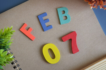 February 7, Cover design in natural concept with a brown notebook and colorful wooden alphabet.