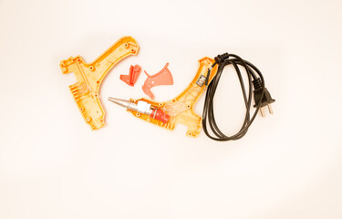 A close-up shot of a damaged hot glue gun with pieces of dried hot glue. 